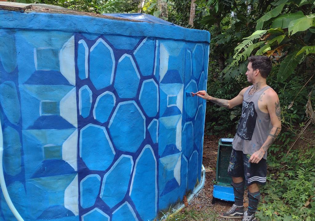 Chico pintando una pared de azul como parte de un voluntariado de verano