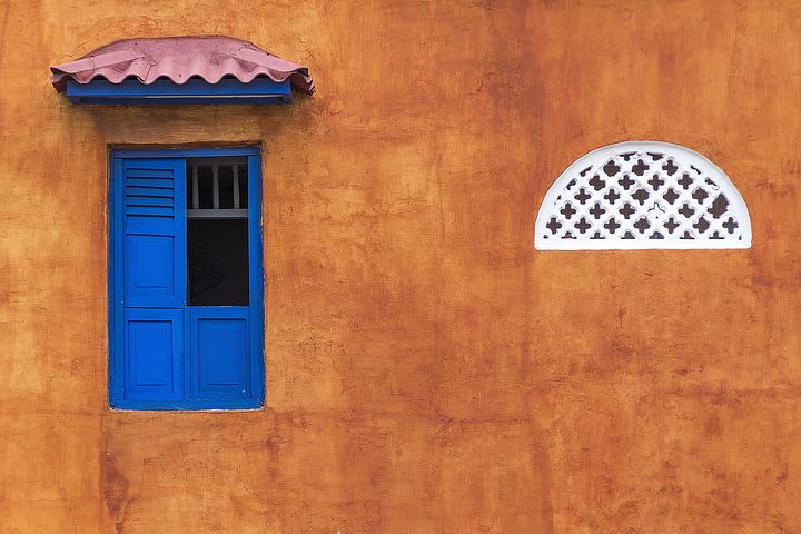 10 cosas que puedes hacer en Cartagena con poco dinero - Worldpackers - fachada de pared colorida con ventana azul en cartagena