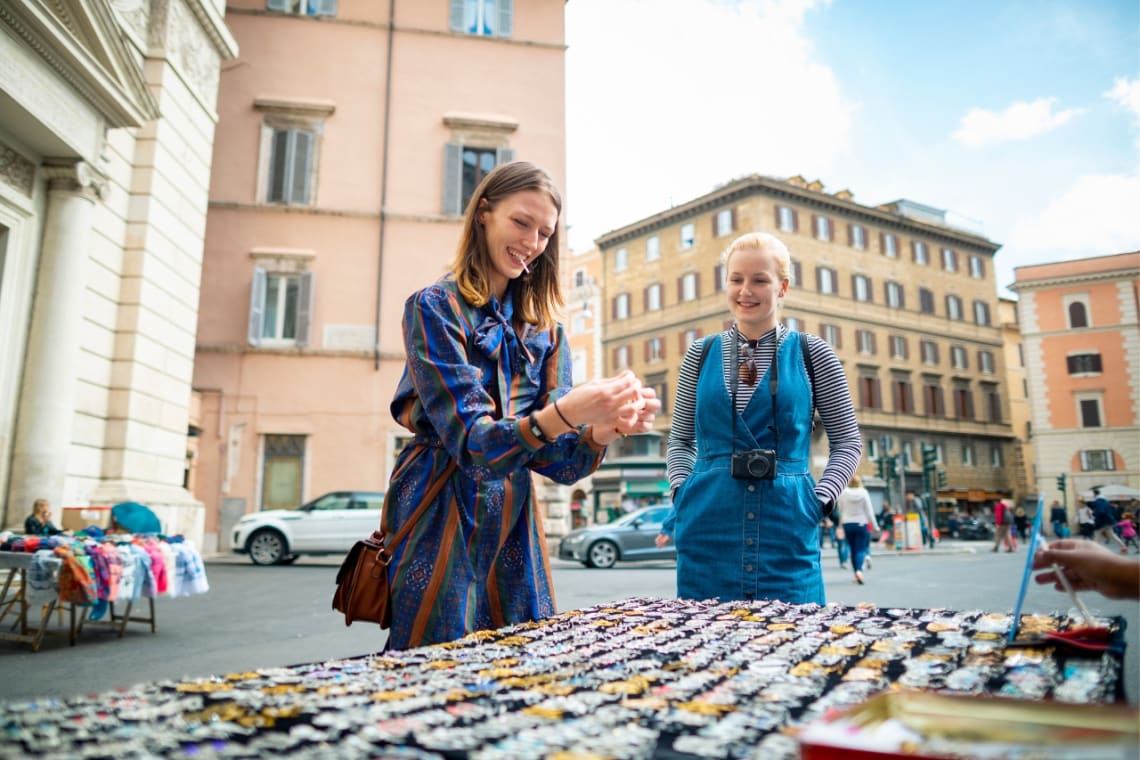 Dos chicas comprando artesanías a un vendedor local