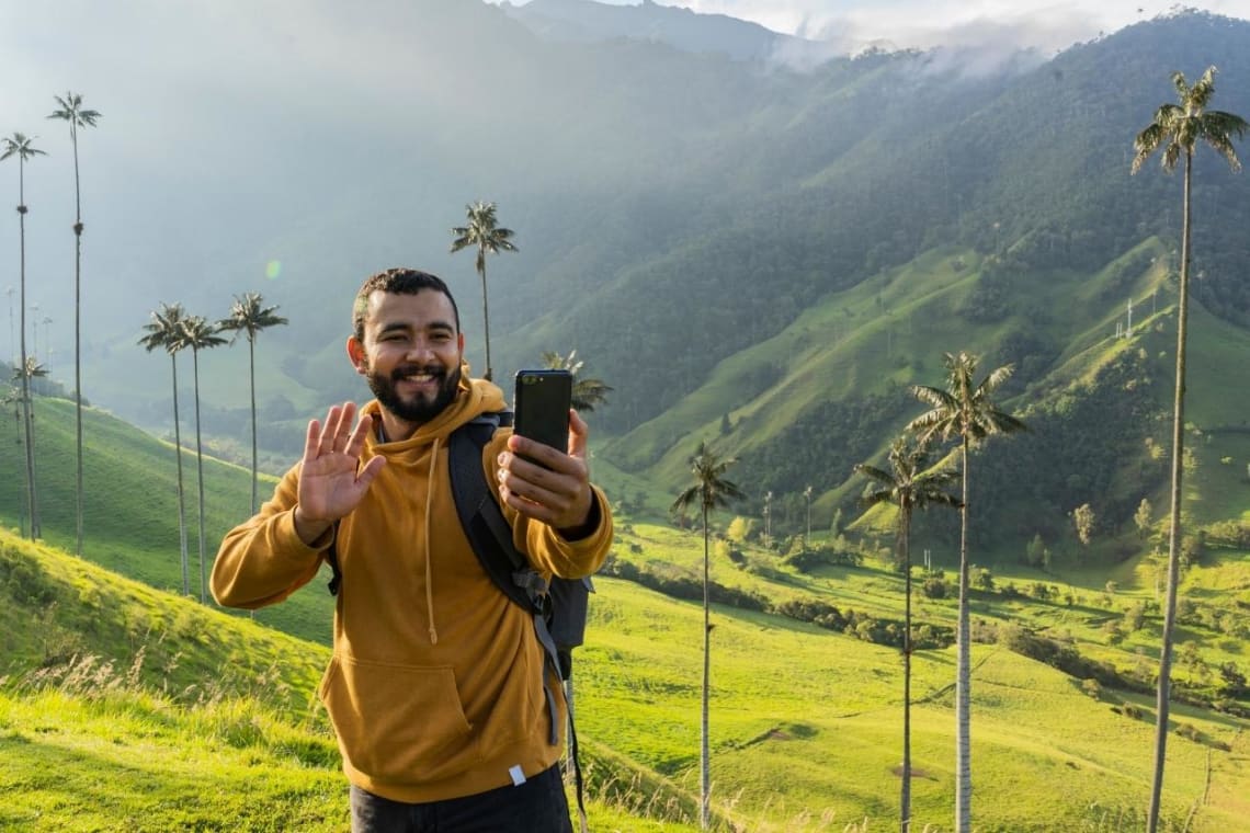 Joven grabándose con celular en paisaje de montaña