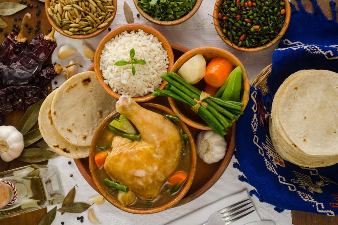 Cazuela de pepián con arroz, tortillas y verduras como acompañamiento