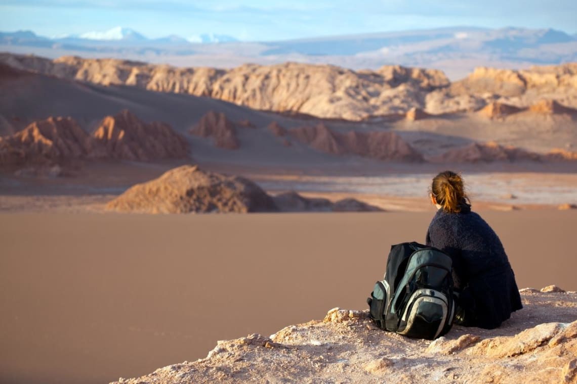 Chica sentada en una roca observando el Desierto de Atacama 