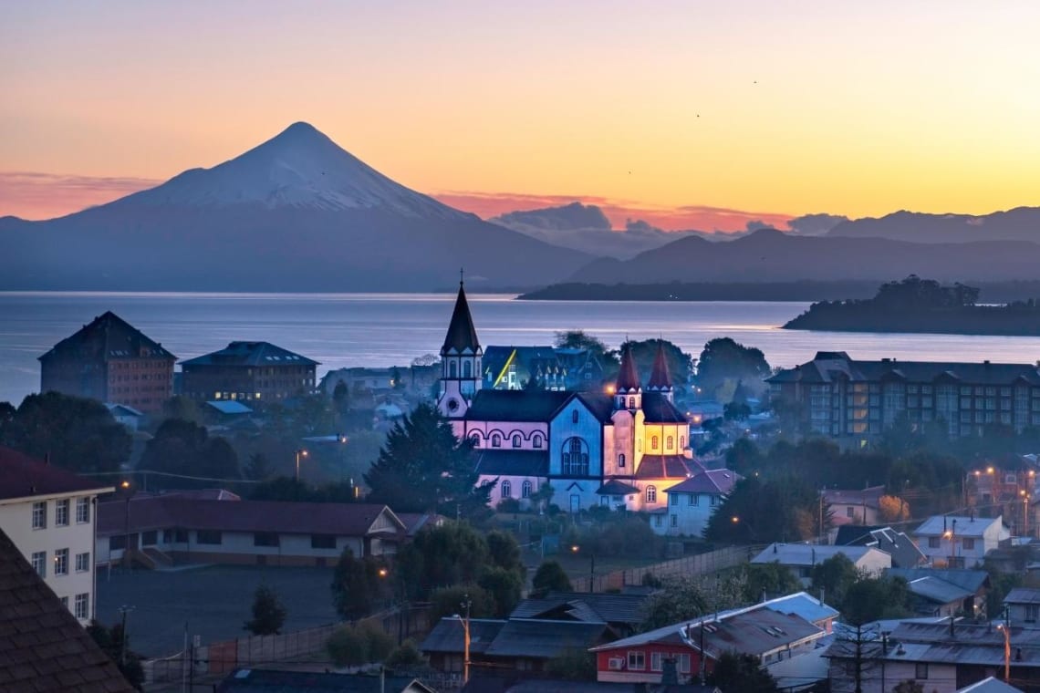Vista de Puerto Varas con iglesia iluminada de colores y volcán de fondo