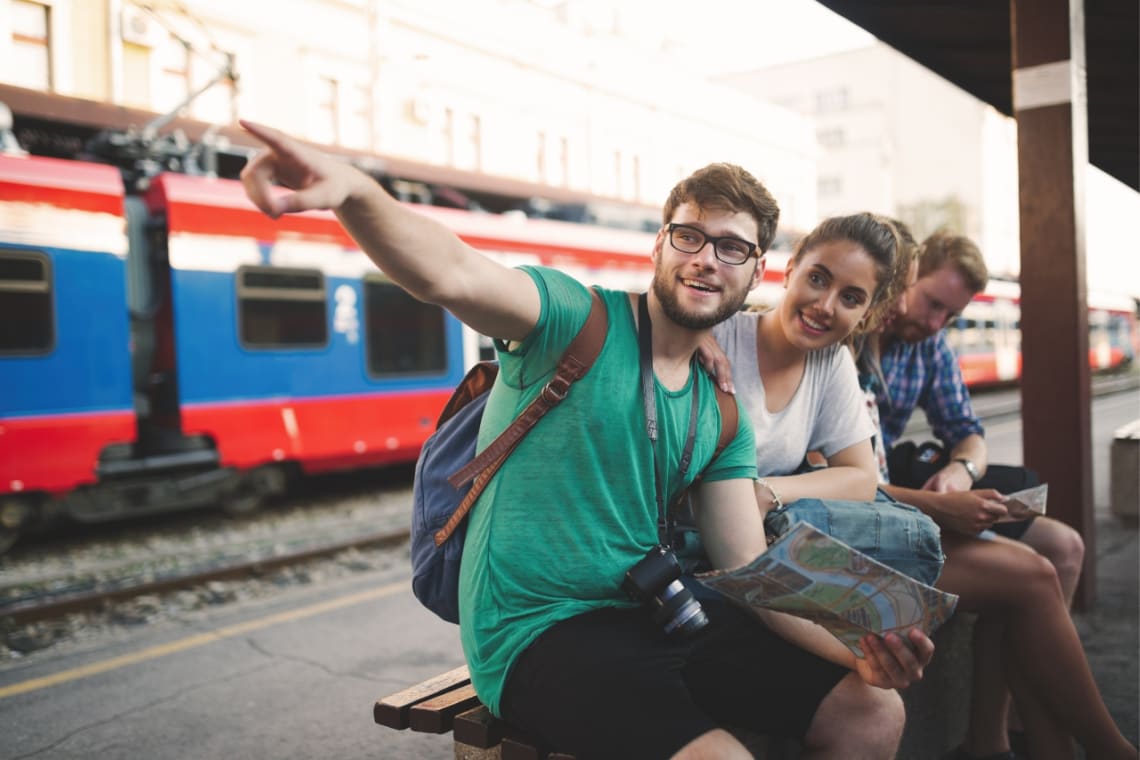 Boy and girl travel partners in a railway station with a map in hand pointing where to go