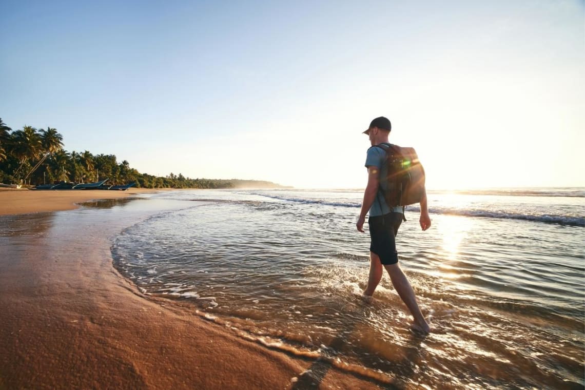 Guy walking in a beach at sunset