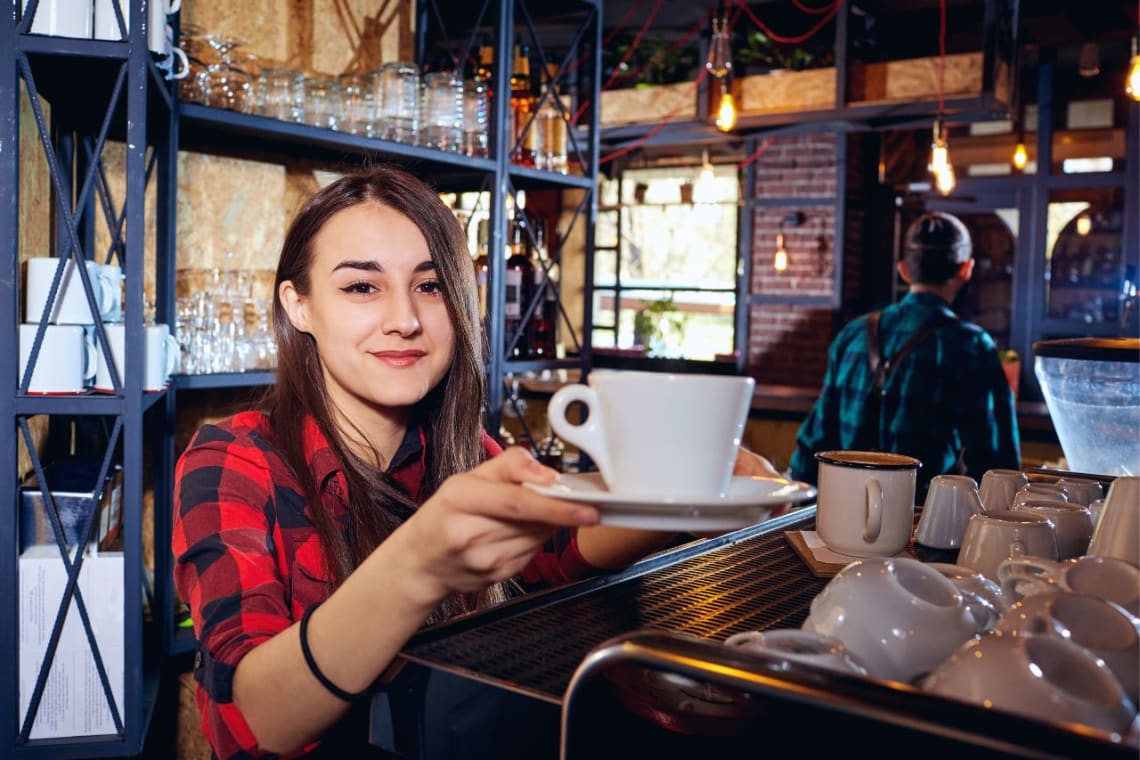 Chica trabajando como barista en Dinamarca, uno de los mejores países para trabajar