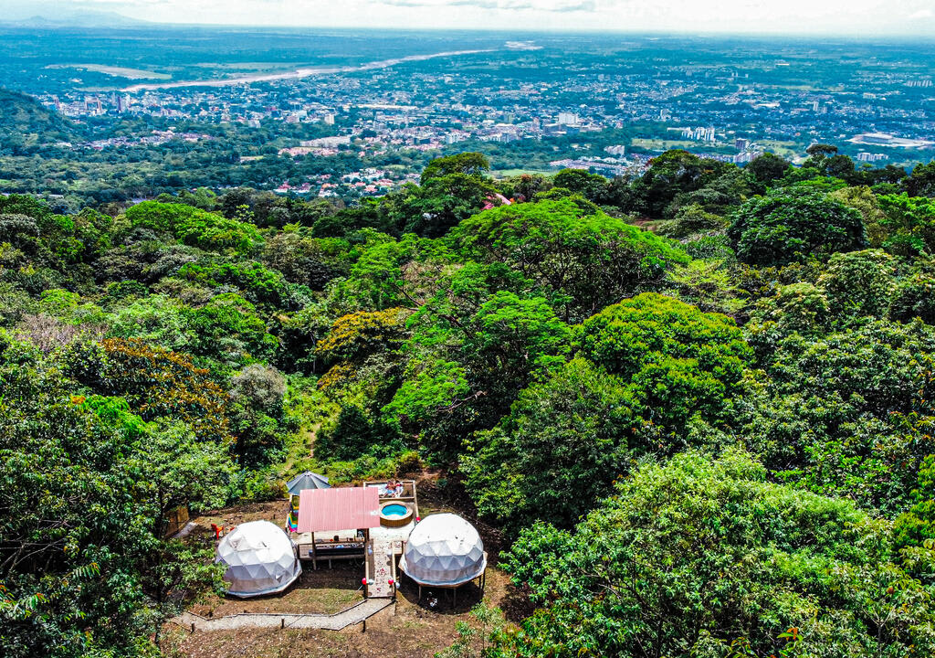 Glamping Colombia: vista aérea de Itawa, en la que se ven dos domos y jacuzzi en la montaña rodeado de selva 