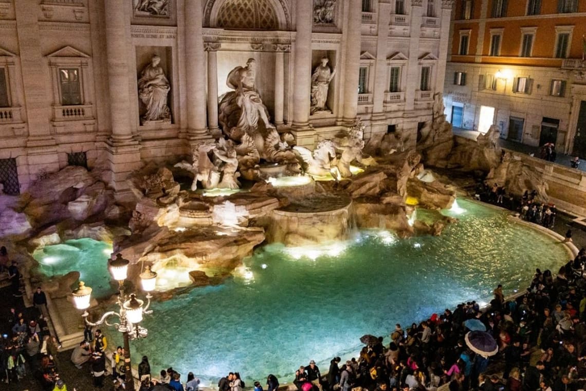 Fontana di Trevi de Roma llena de turistas. Evitar la temporada alta es fundamental para viajar barato por Italia