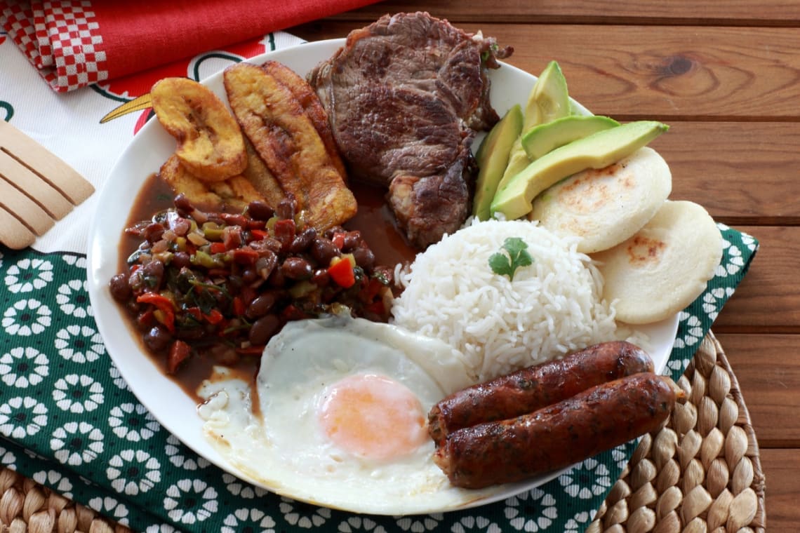 comidas típicas de Colombia: bandeja paisa con arroz, huevo frito, chorizo, aguacate, trozo de carne, plátano frito, frijoles y arepas