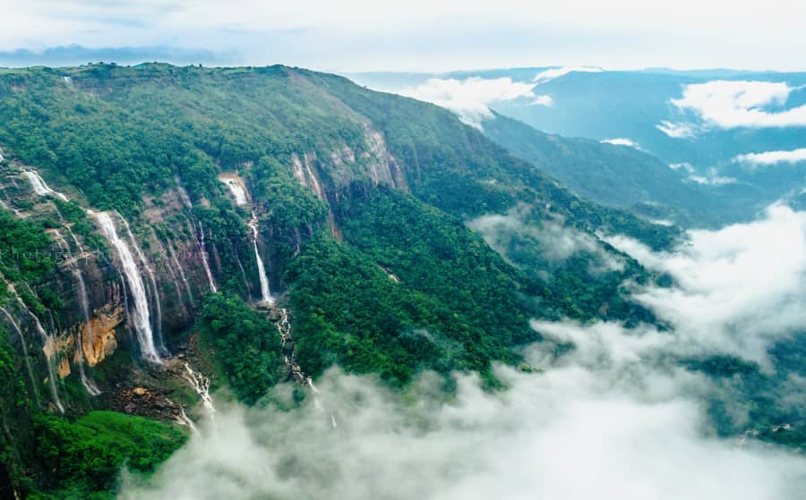 Waterfalls pouring off green cliffs in Meghalaya