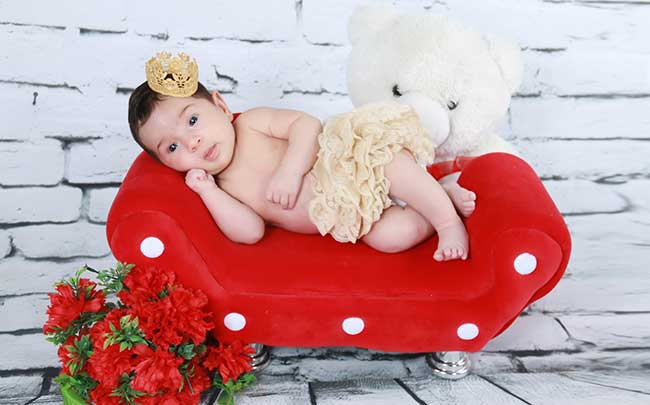 A baby is posing for the camera waiting for picture to be taken.