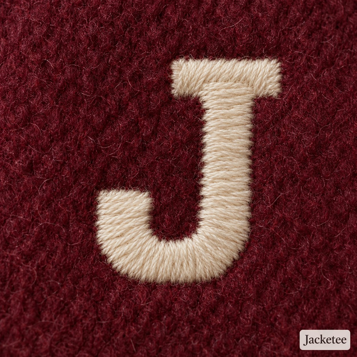 Cream block J embroidered on burgundy wool