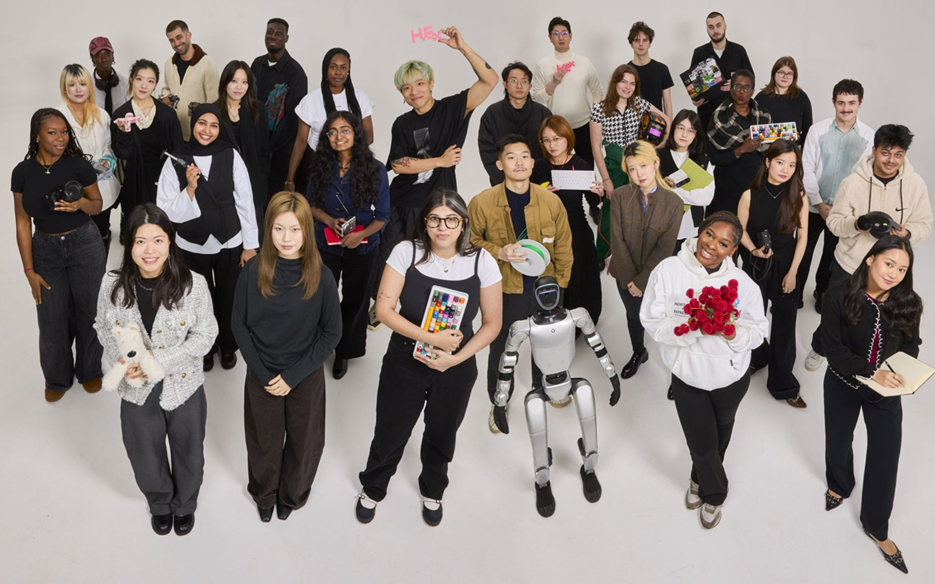 Diverse group of 40+ people standing together viewed from above, mostly wearing black
