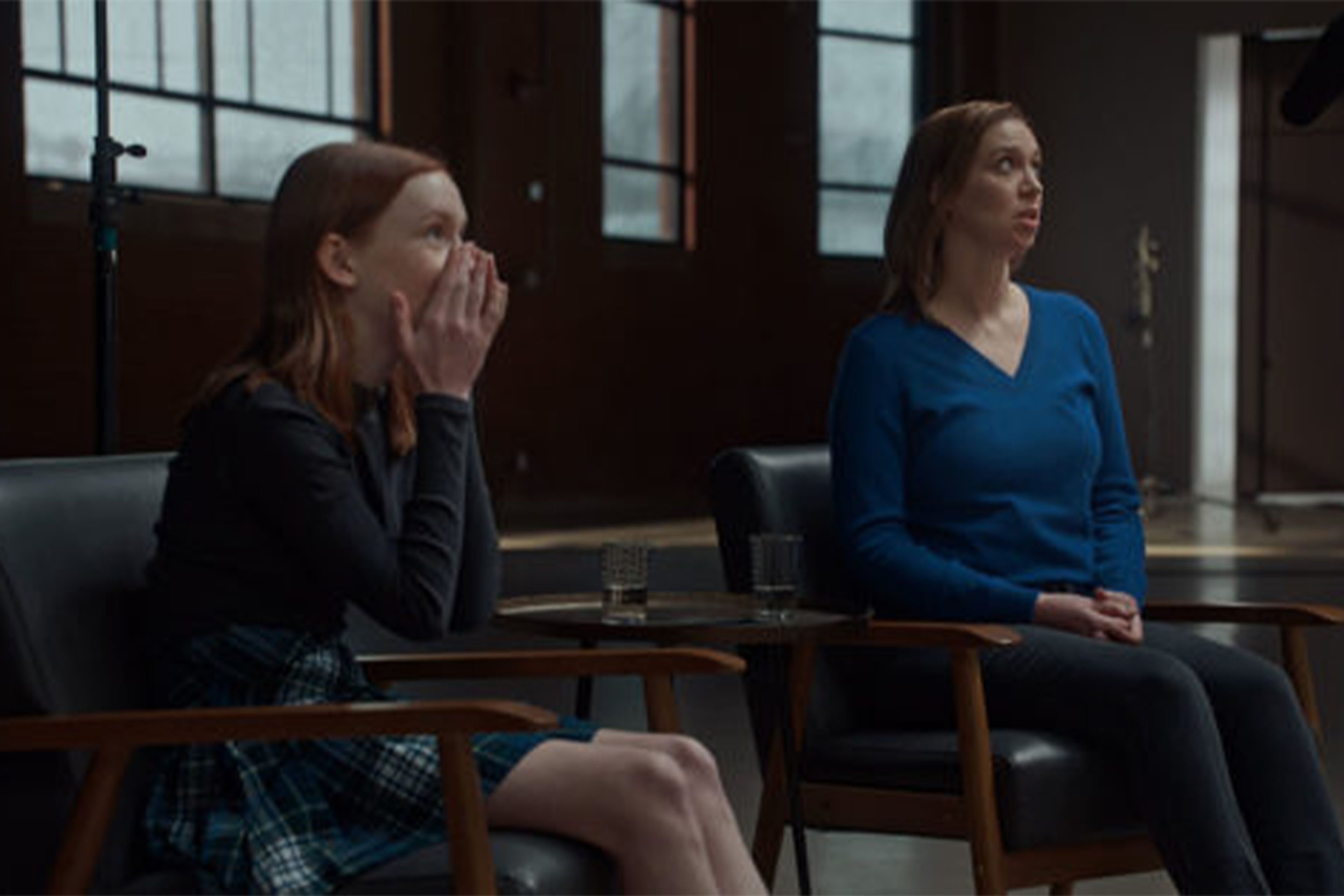 Mother and daughter watching screen, with daughter looking shocked