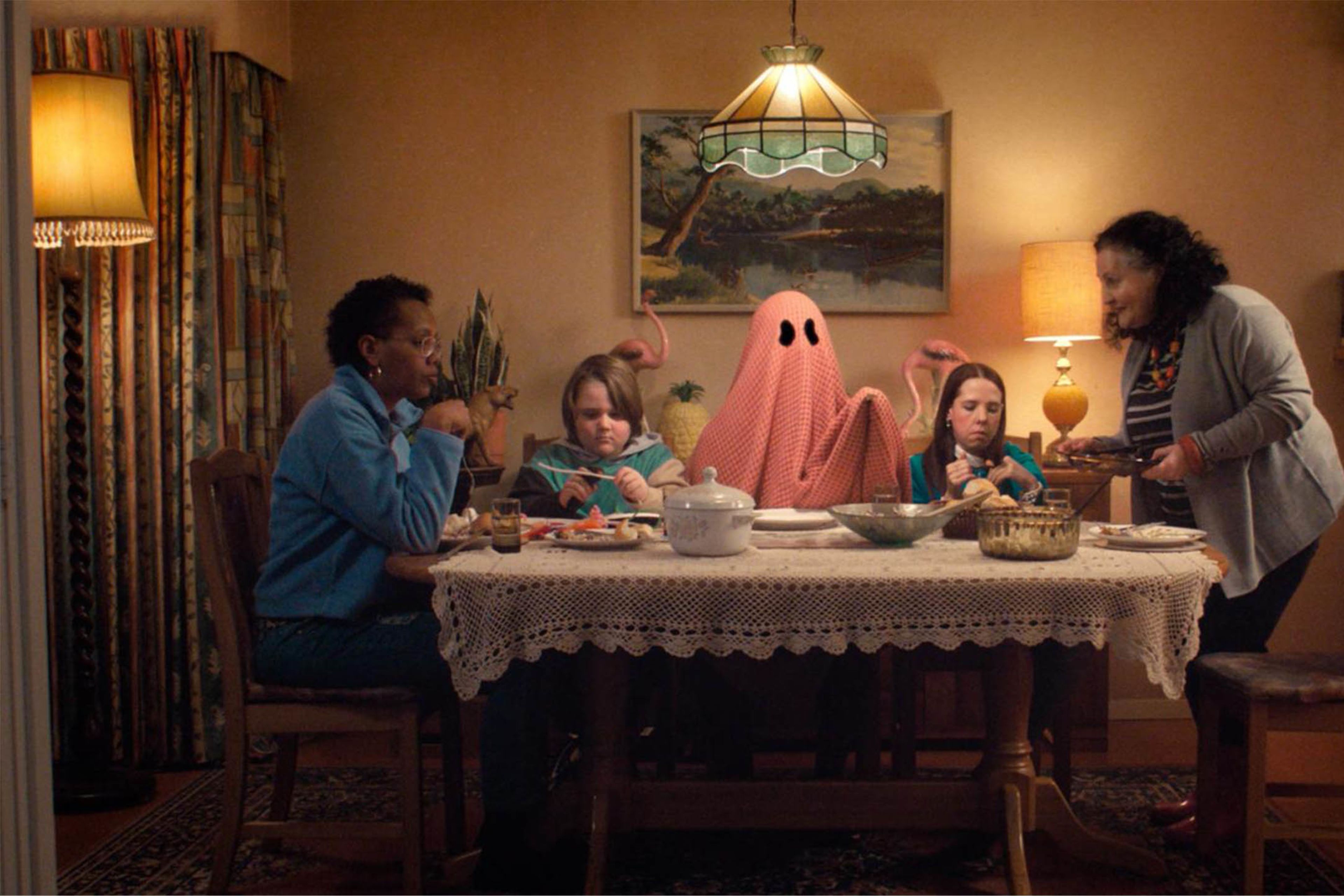 People eating dinner round a table, with one of them dressed as a ghost