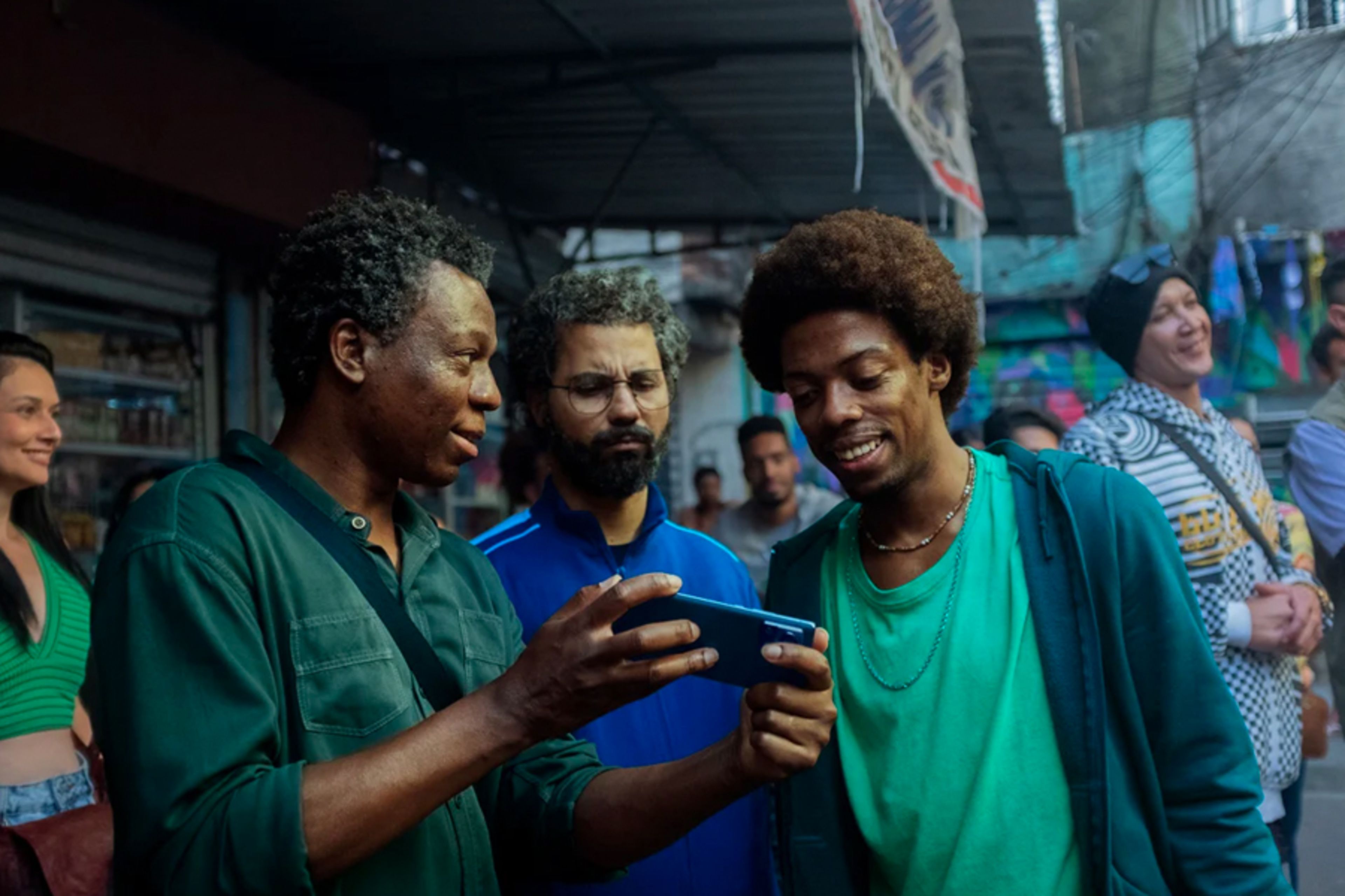 Three men stood together looking at a phone