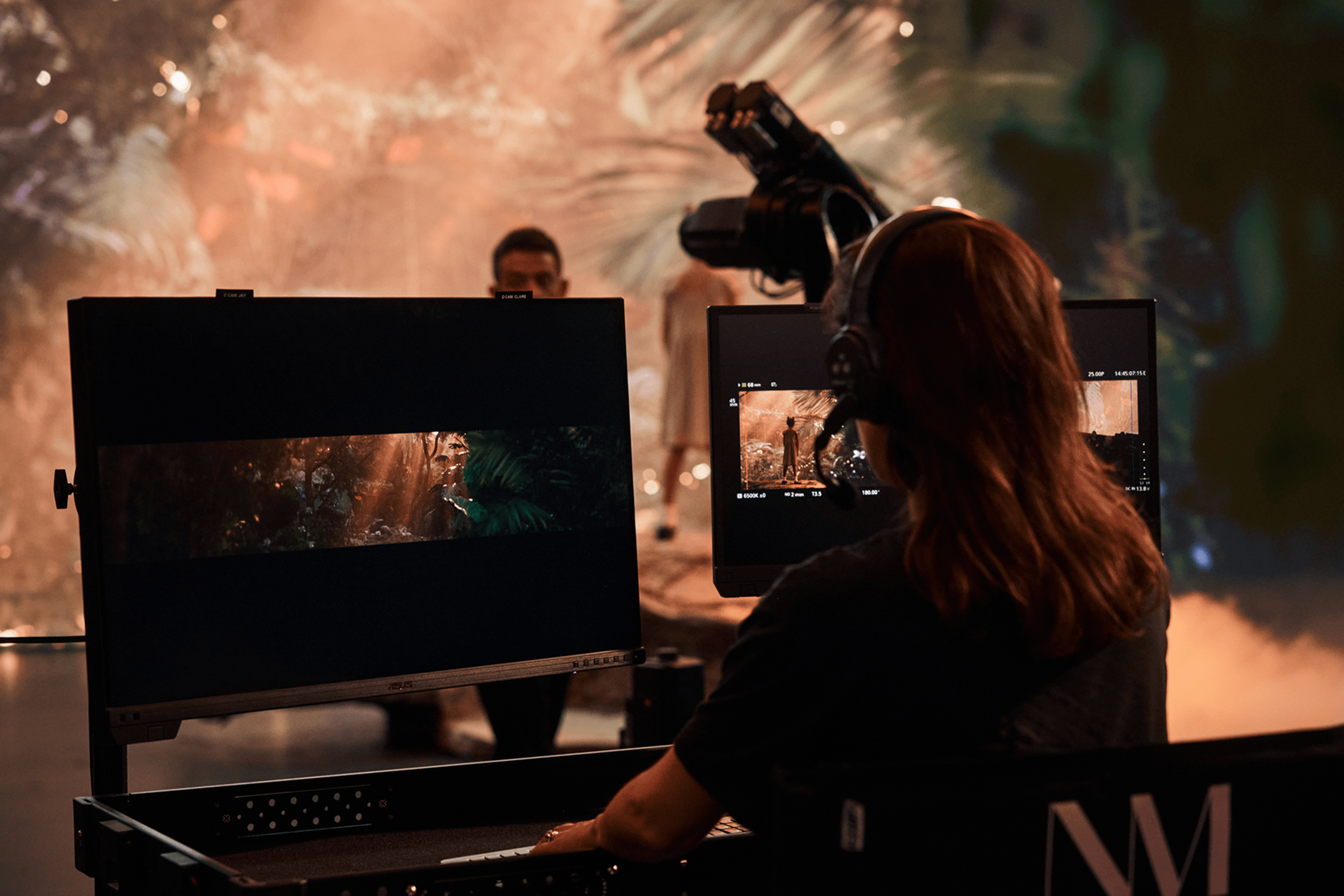 A behind the scenes photo of a person sitting behind two monitors on a production shoot.