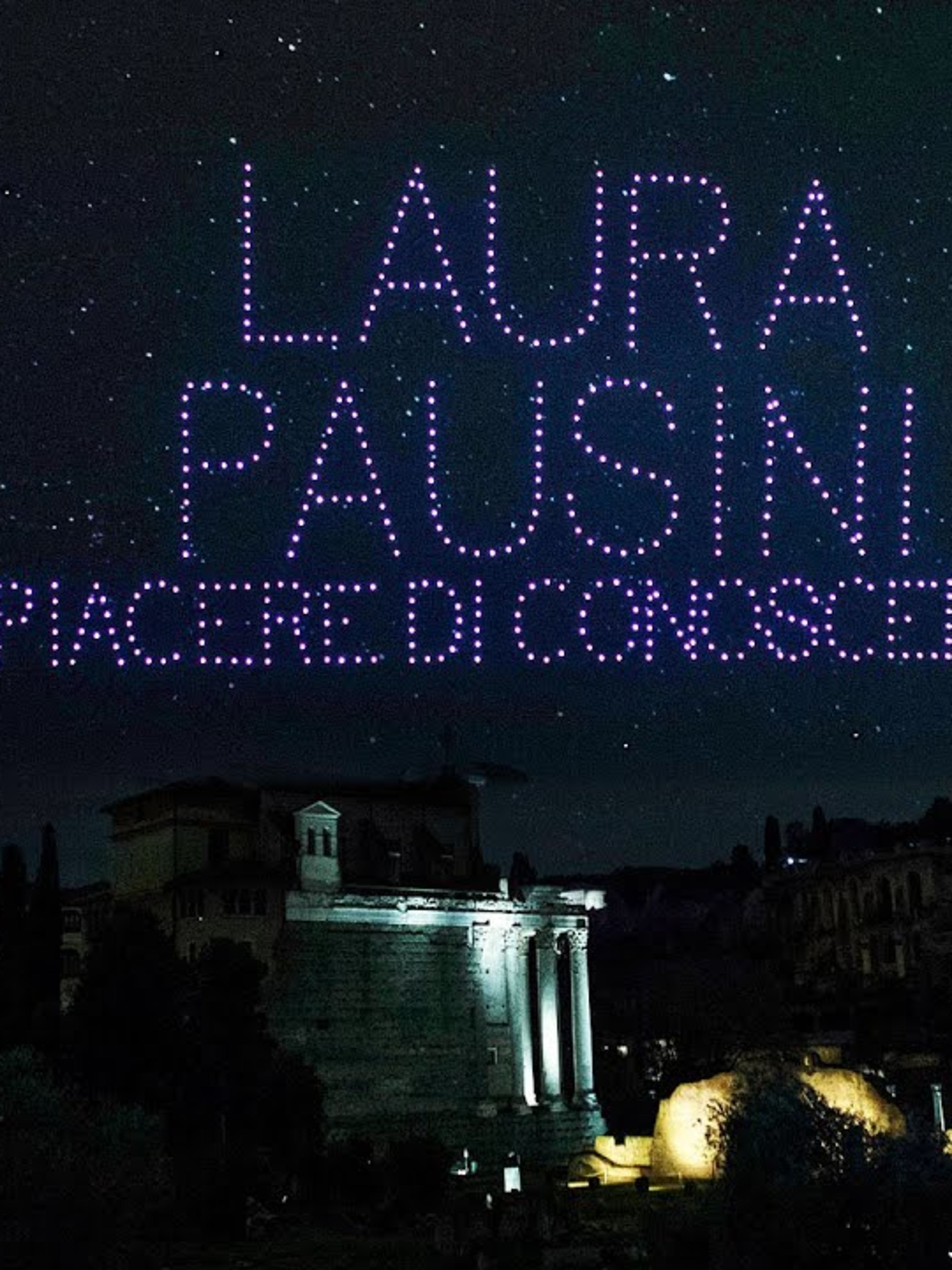 Rome's night sky with the words Laura Pausini Placere di Conoscerti written in the sky by purple drones