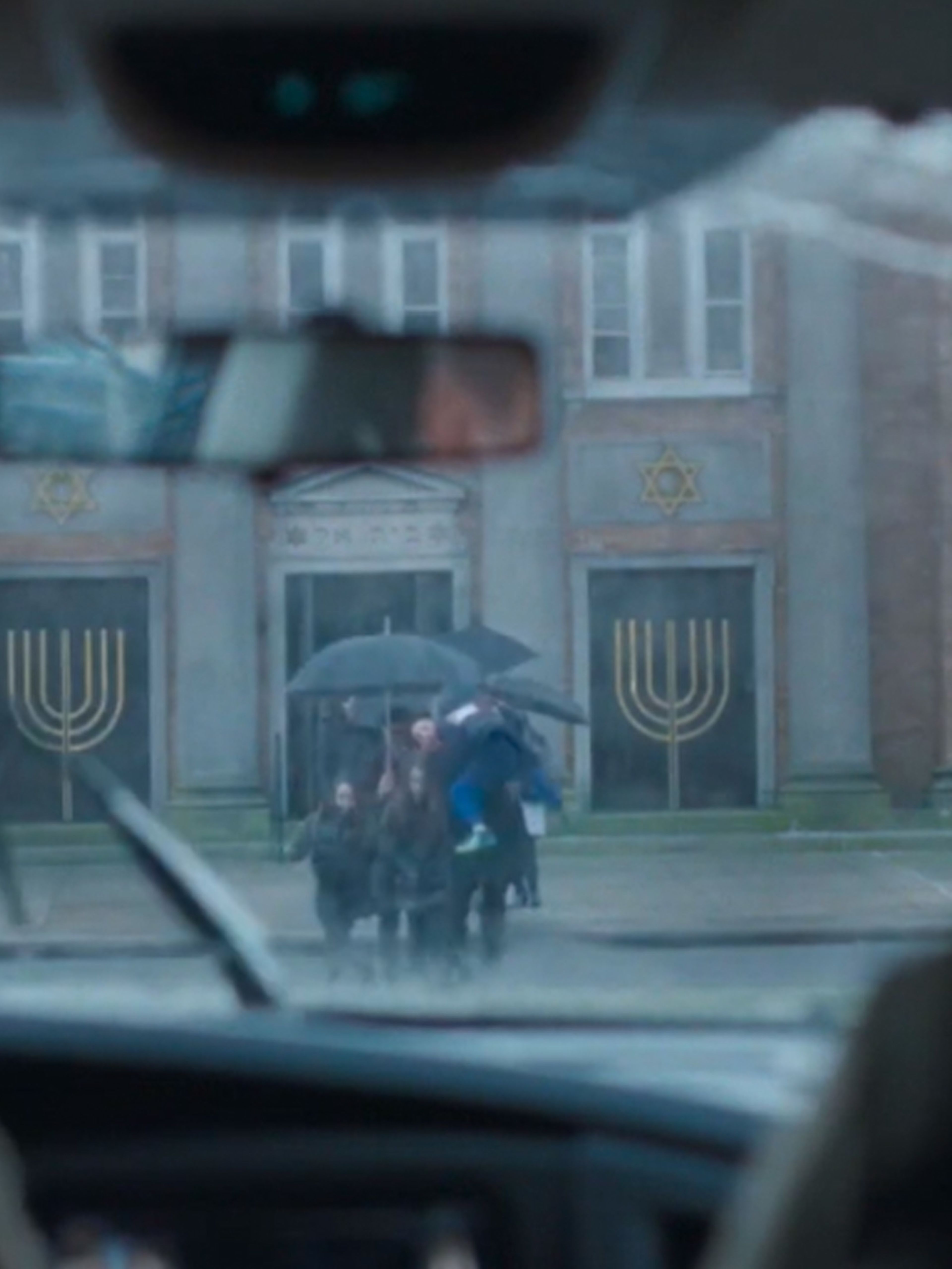 View looking through a car windscreen as a group of people coming out of a synagogue