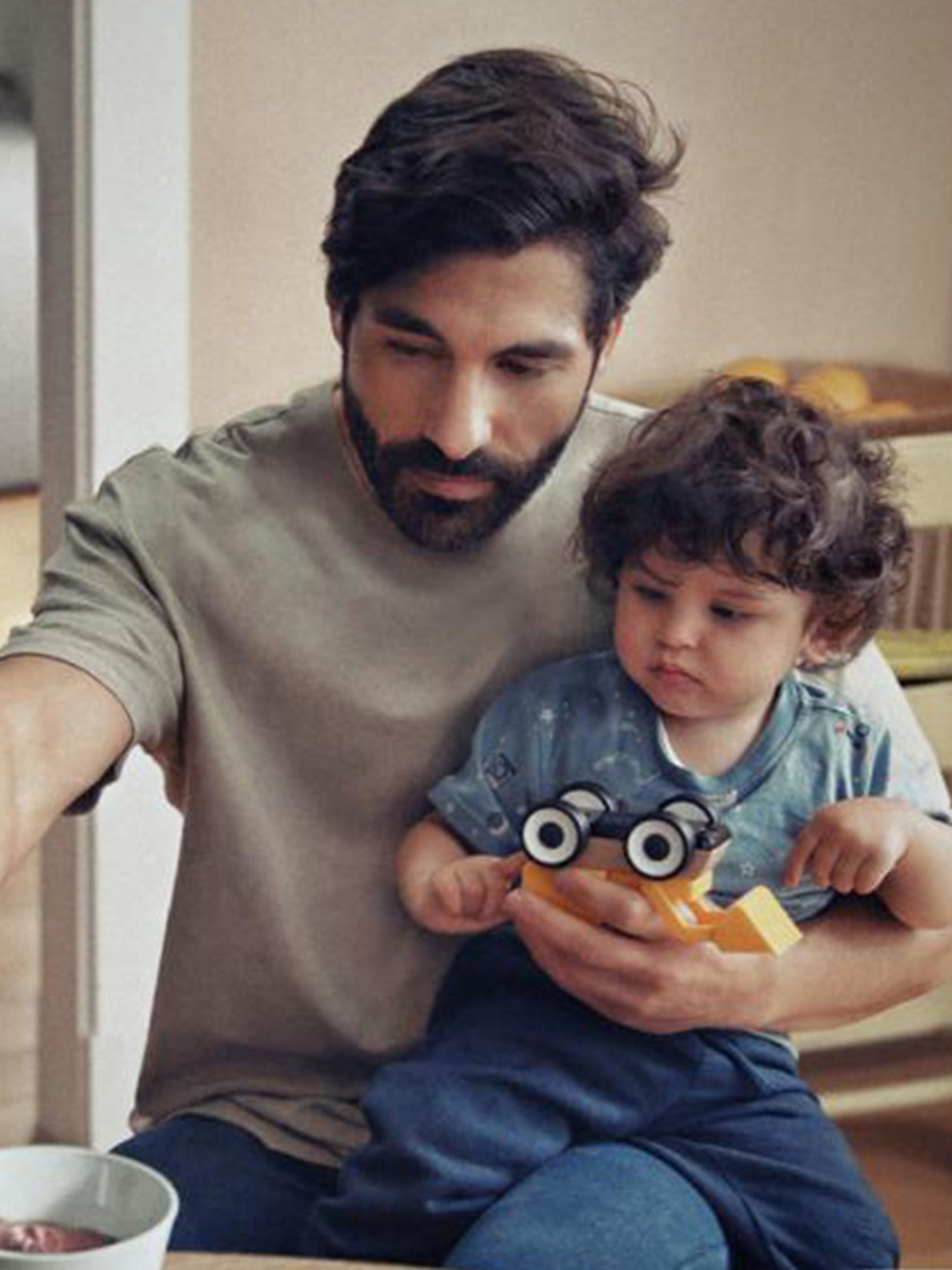 Man feeding a baby with IKEA ANTILOP highchair in background