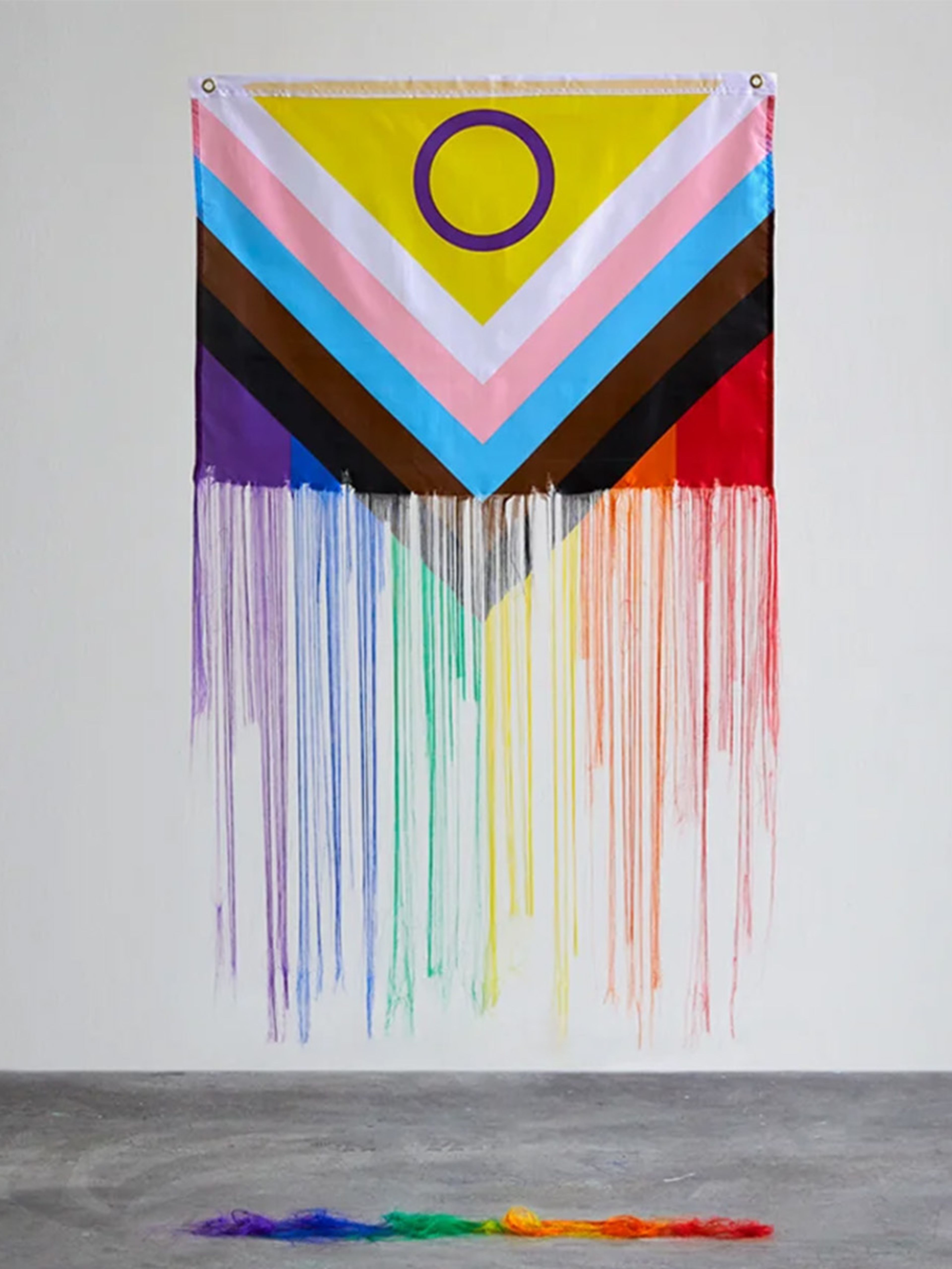 Pride flag being unravelled into piles of thread on the floor