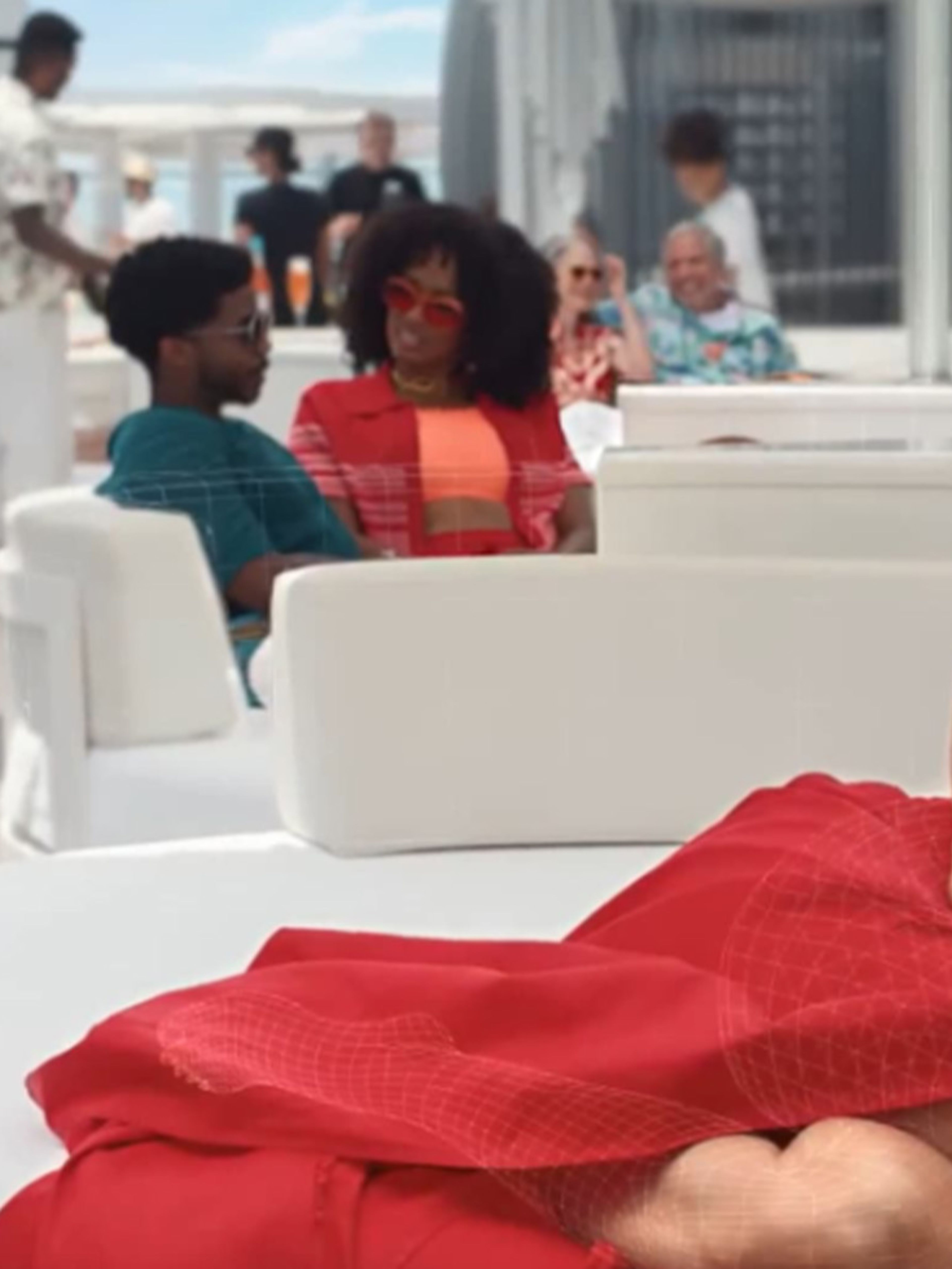 AI image of Jennifer Lopez in a red dress lying on an outdoor couch
