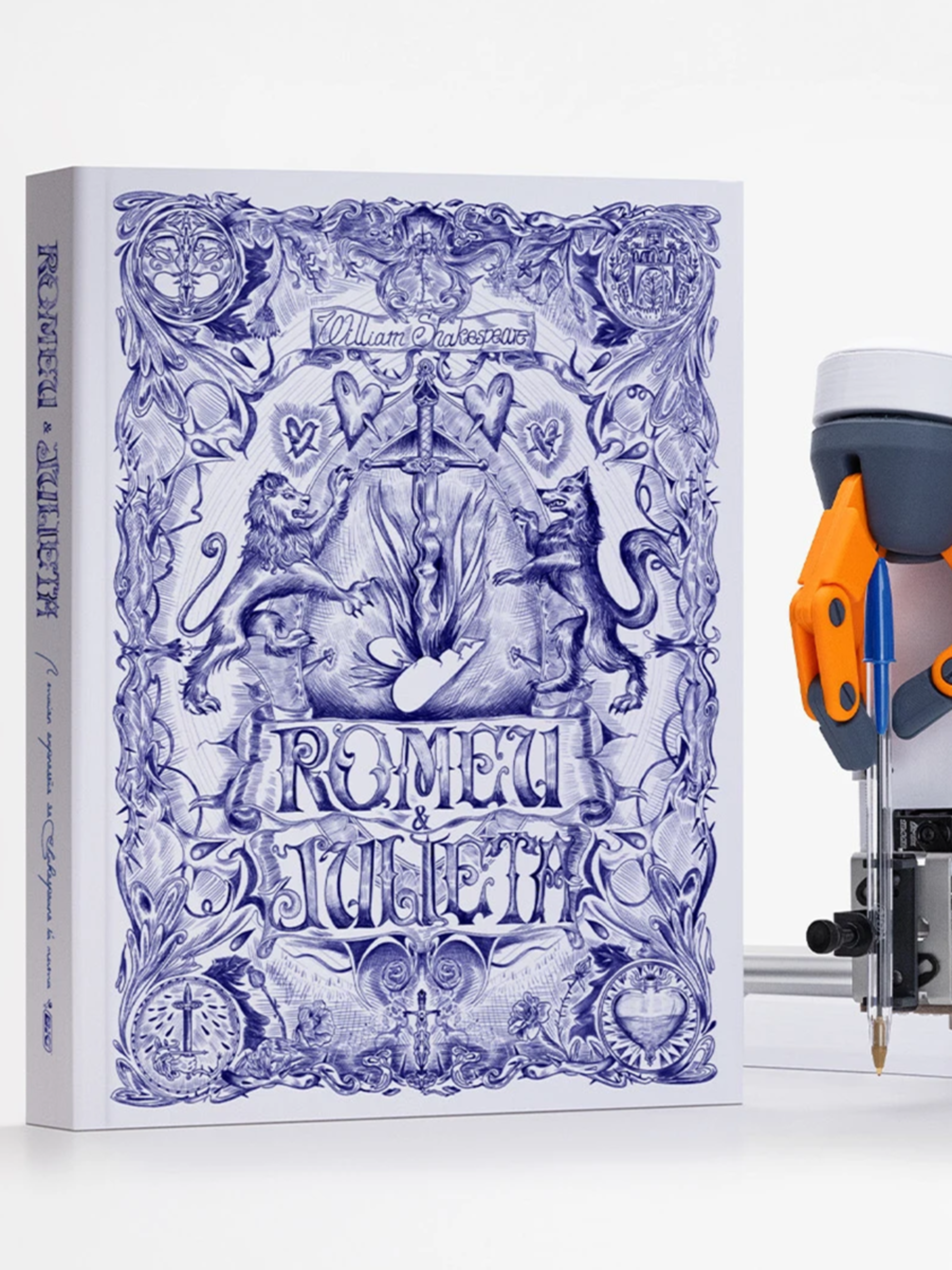 A hardcover edition of Romeo and Juliet with a blue illustrated cover stands next to a white and orange drawing robot. The robot holds a blue pen and appears ready to draw.