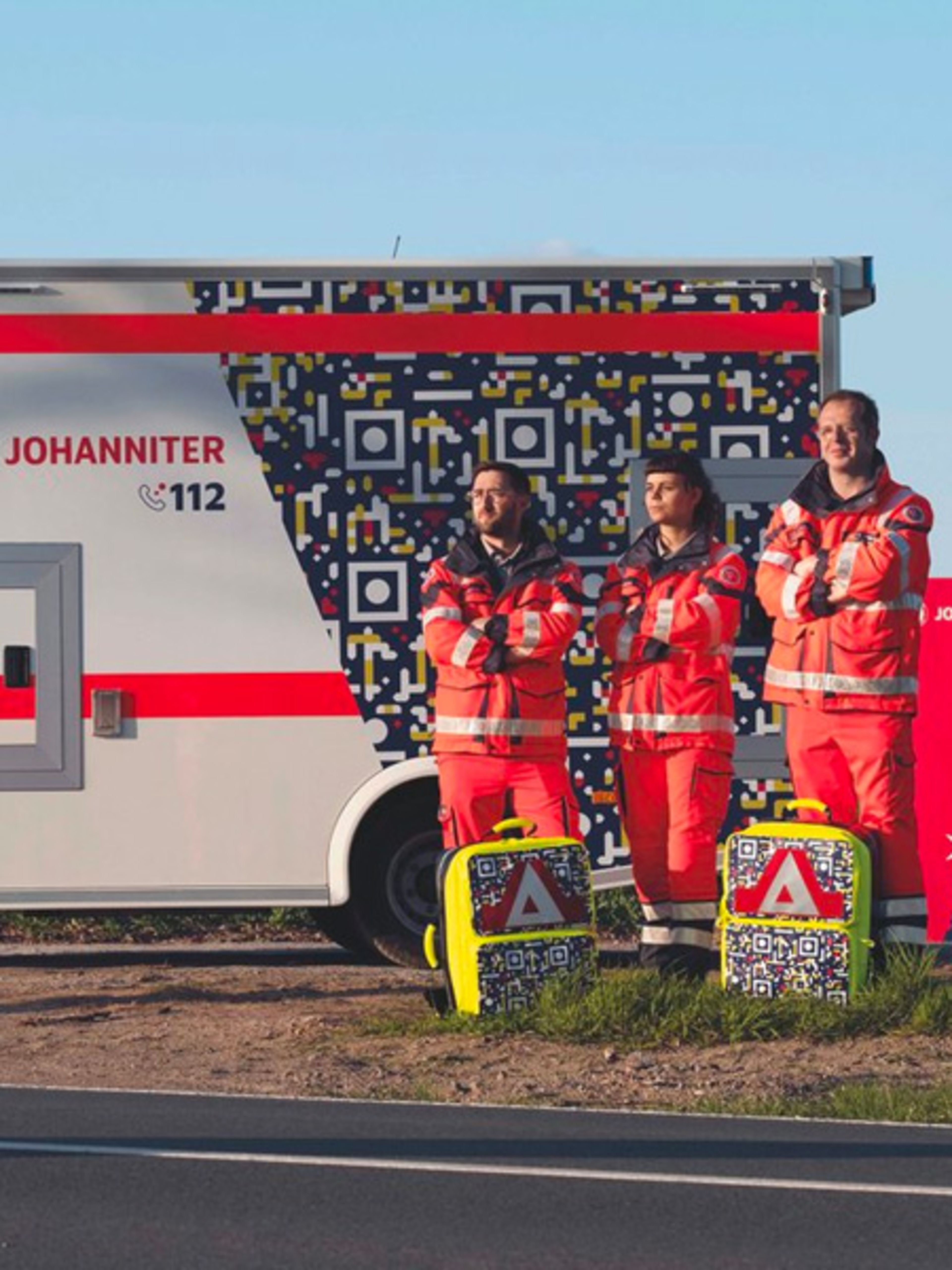 Three people standing next to van and and billboard with a QR code