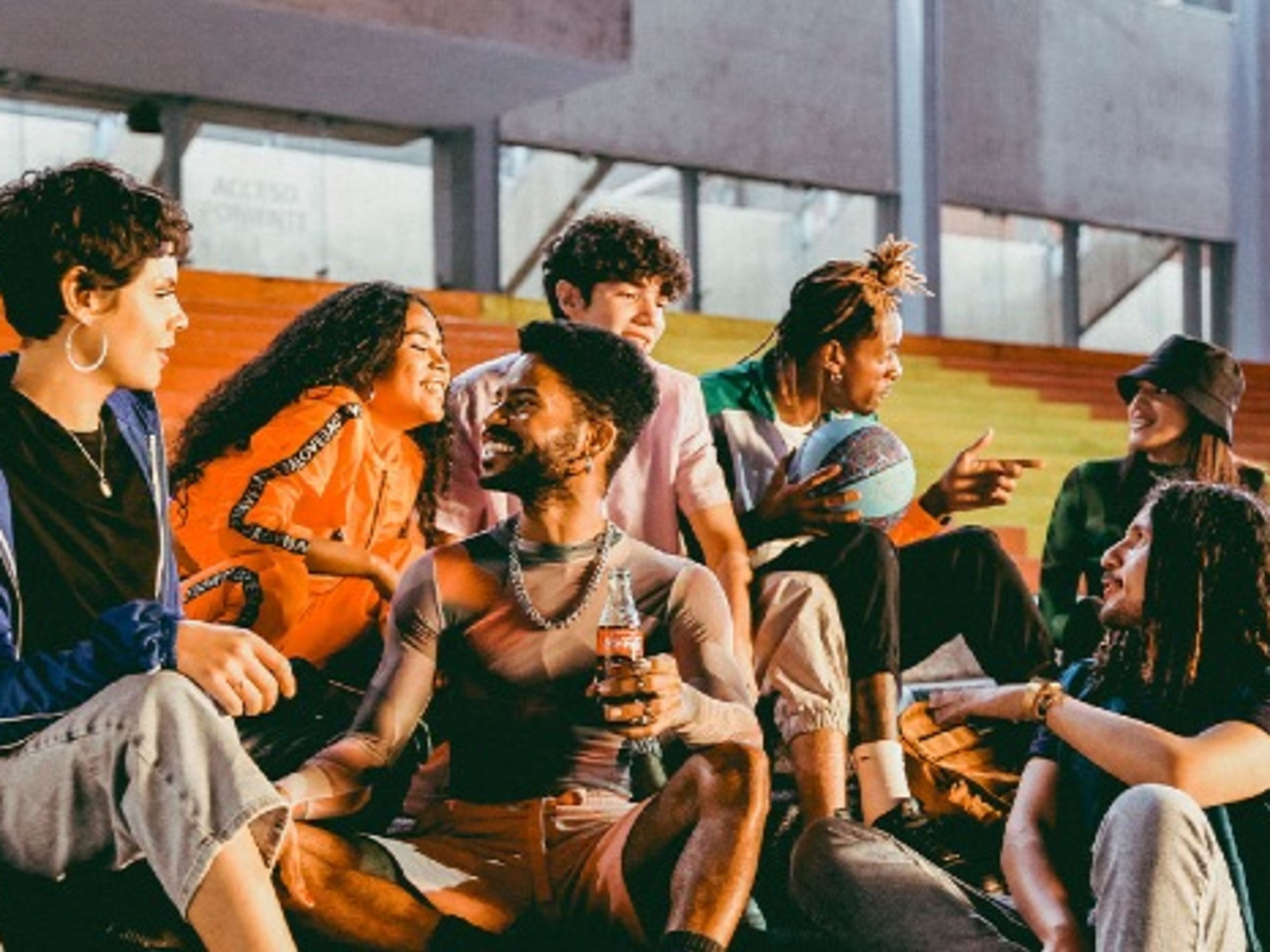 A group of people sat talking and drinking coca cola products