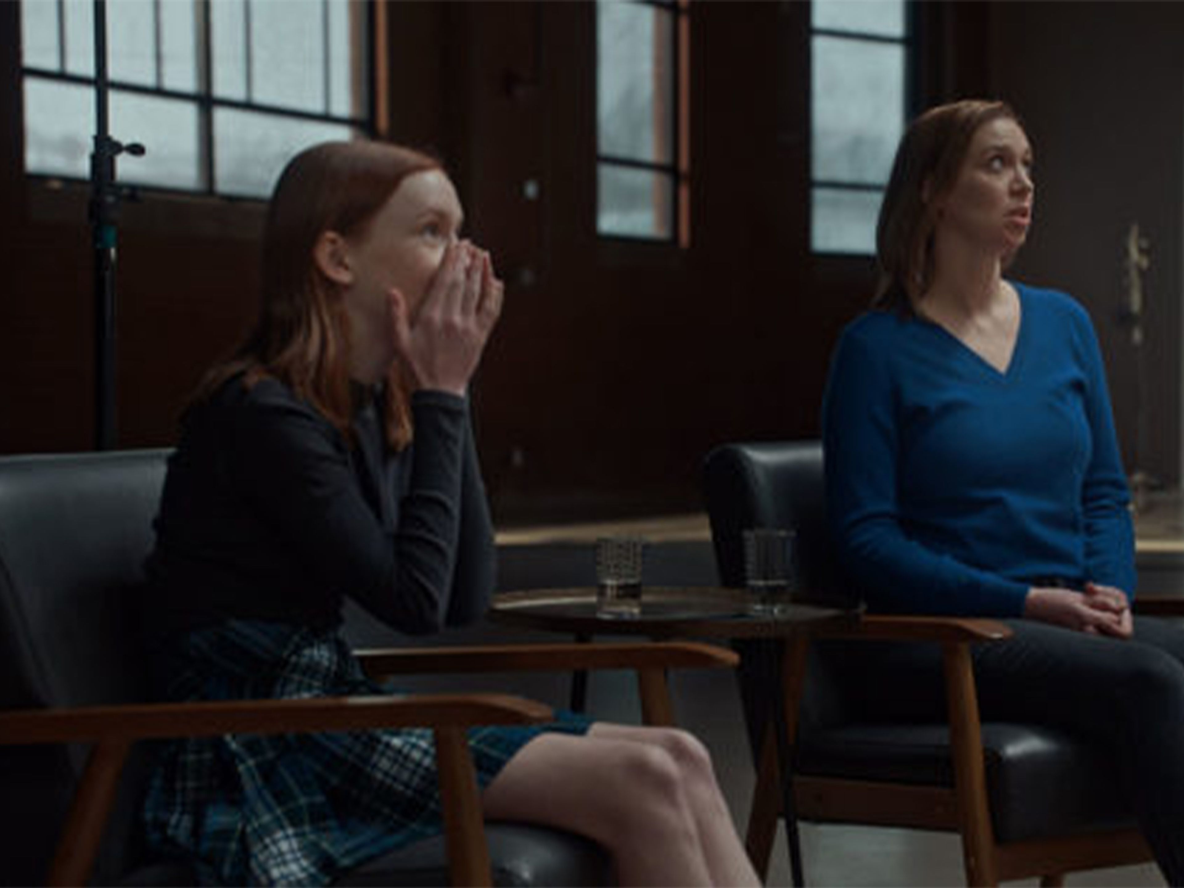 Mother and daughter watching screen, with daughter looking shocked