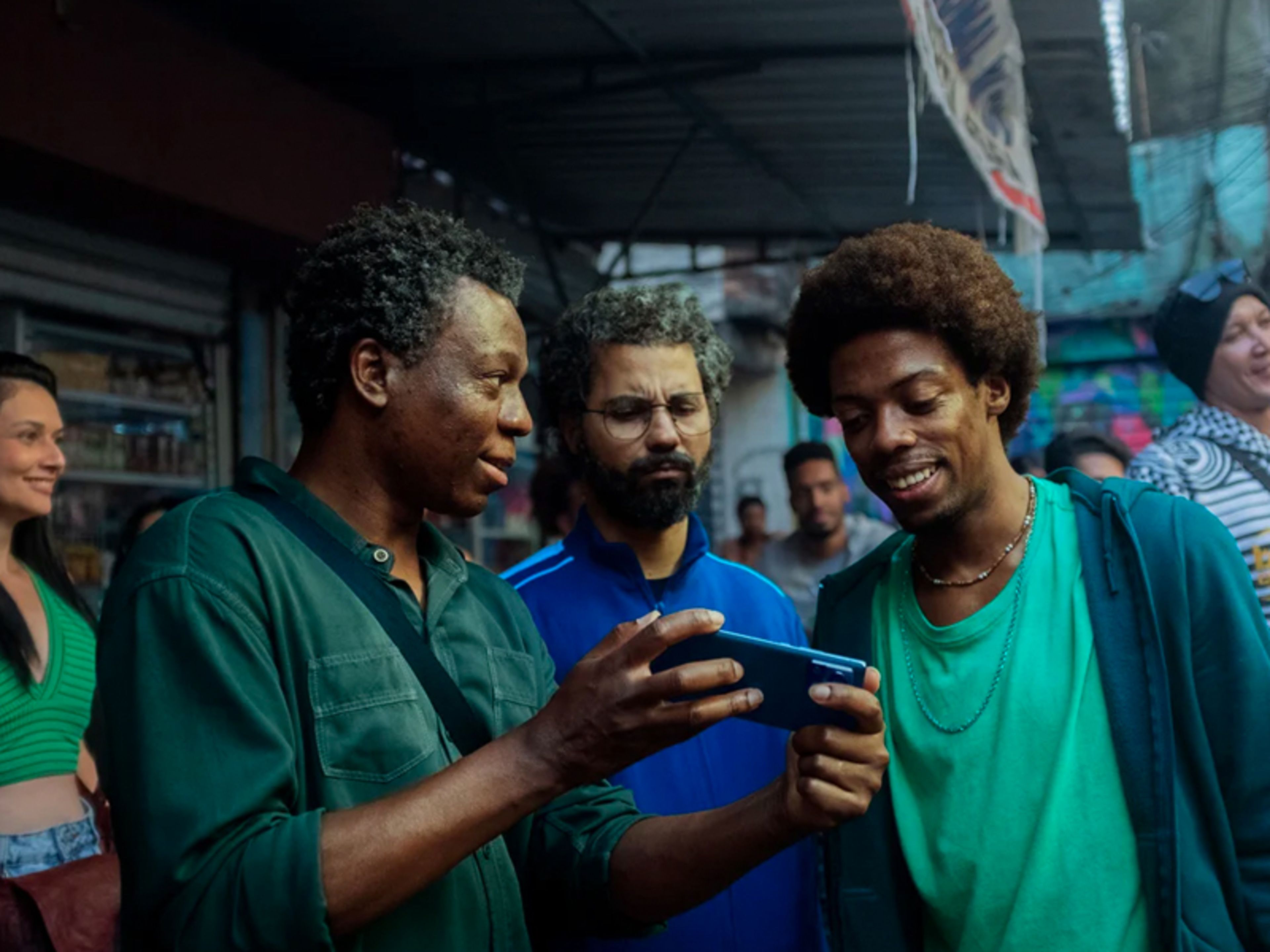 Three men stood together looking at a phone