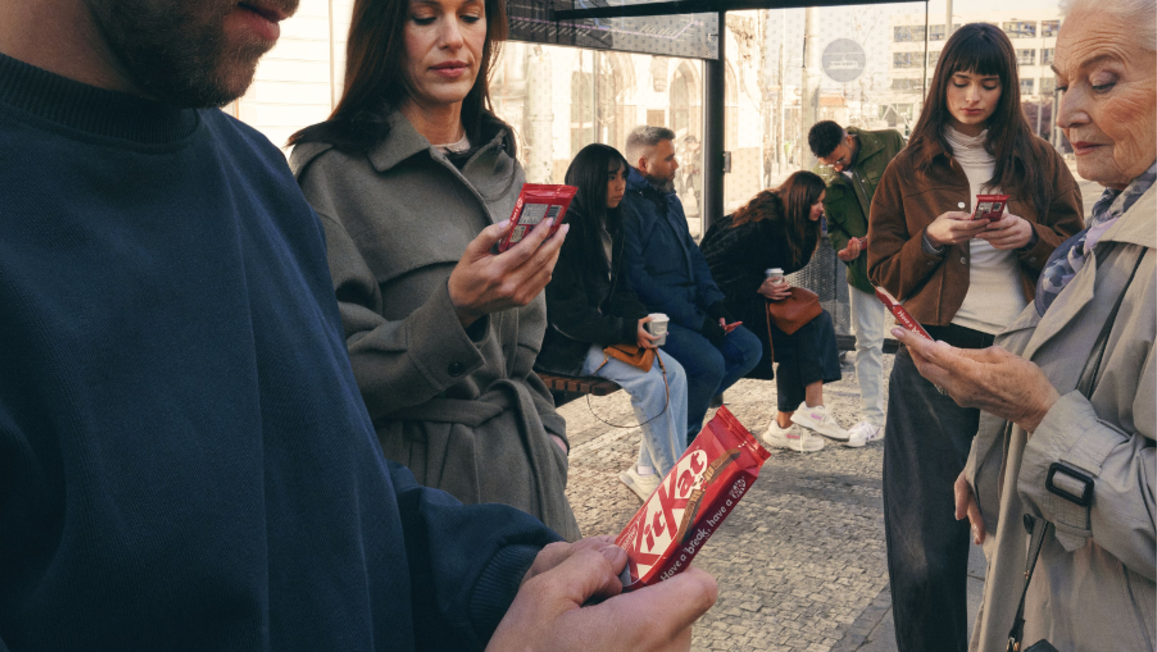 People in a crowd looking down at KitKat bars as if they were smartphones