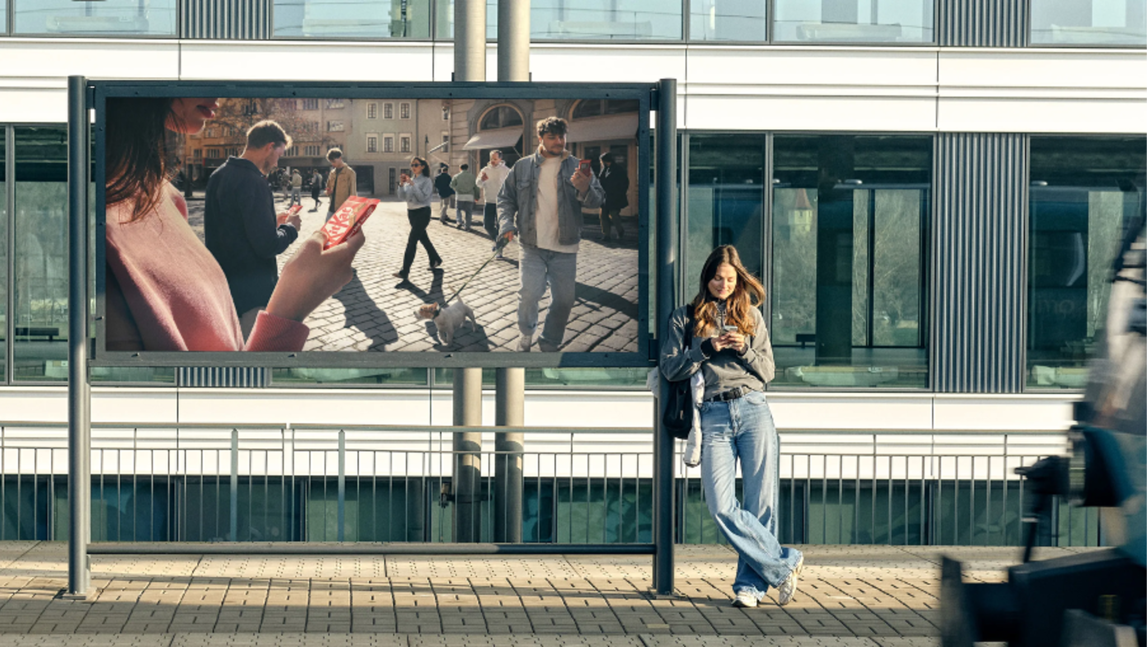 Person stood in front of a billboard on their phone