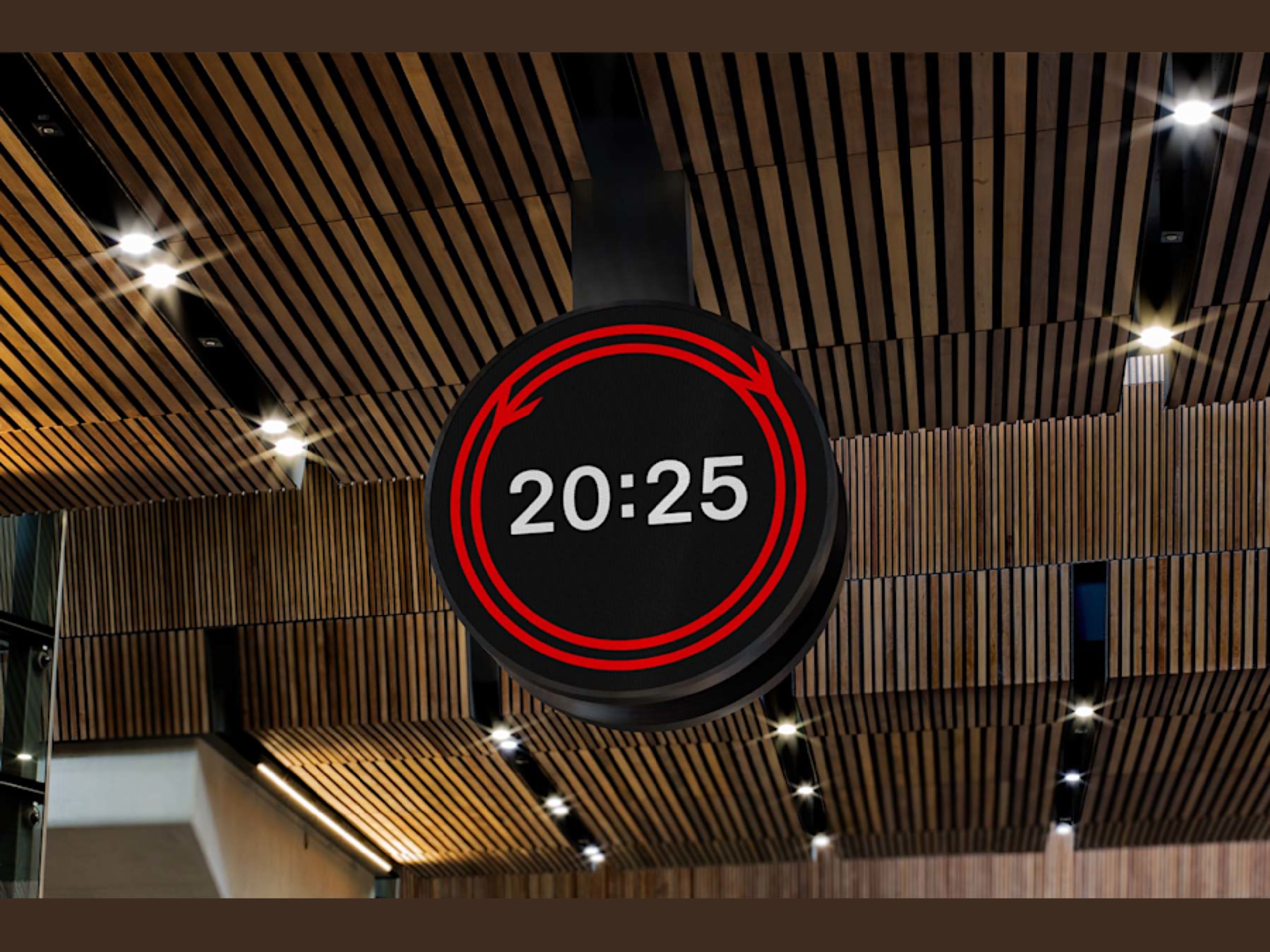 A black circular sign displaying '20:25' in white text, surrounded by red circular arrows, hangs from a modern wooden slatted ceiling with spotlights