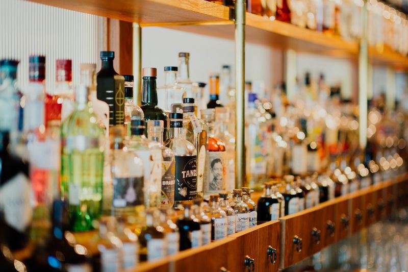 Foto de una estantería en una tienda de licor con rack de degustación