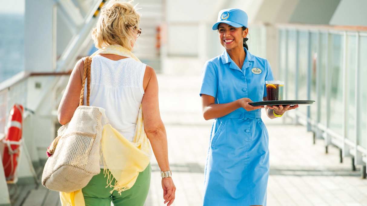 Waitress with drinks walking on deck, guest walking on deck