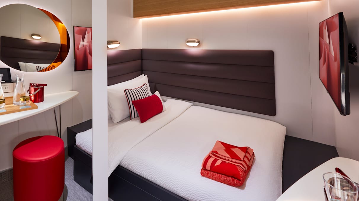 View of a bed and mirror in a Solo Insider Cabin on a Virgin Voyages cabin