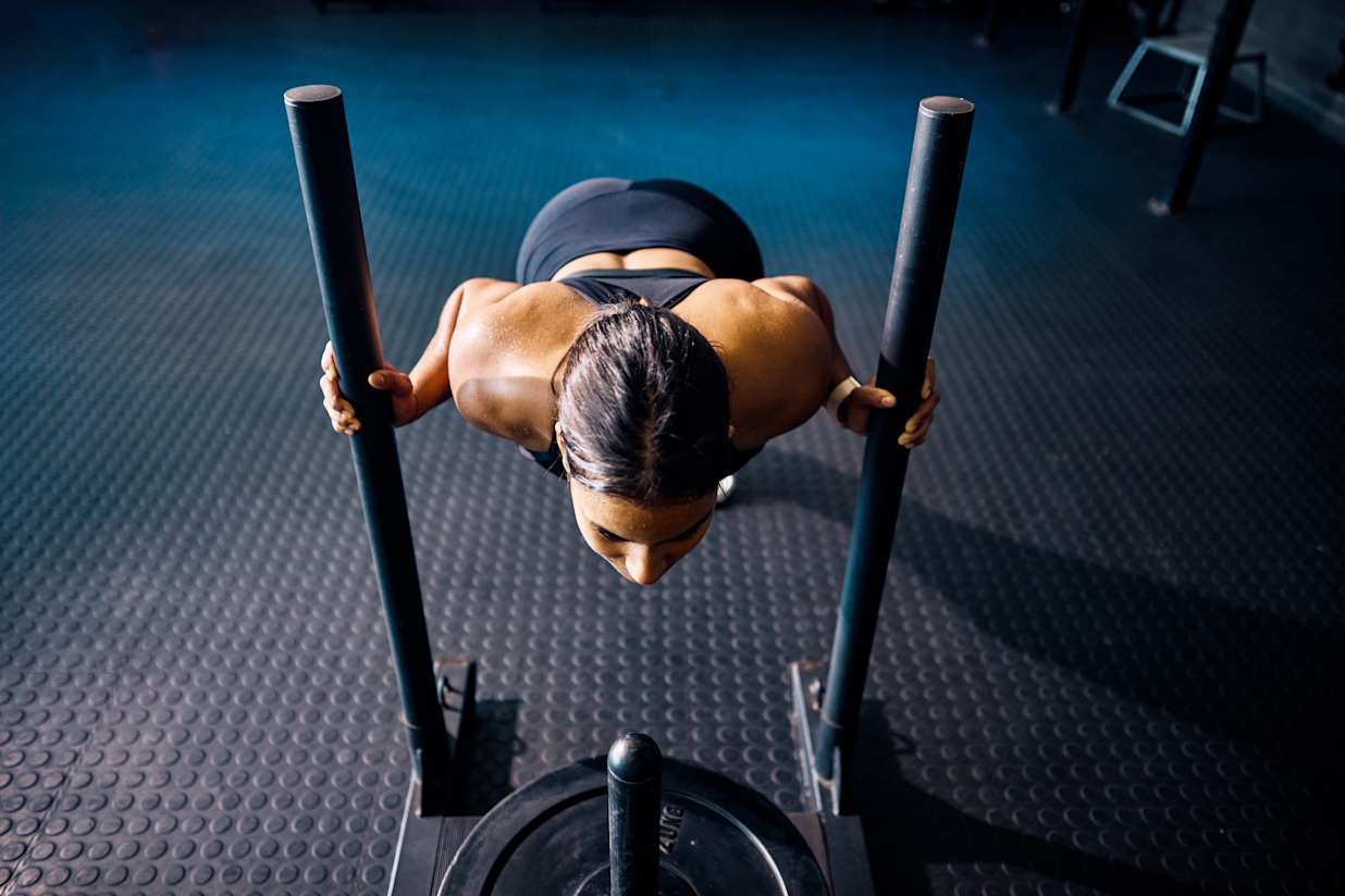 Woman pushing sled in HYROX training