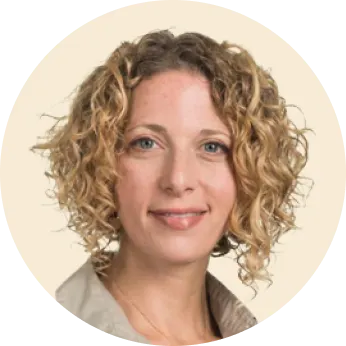 woman with curly hair smiling, professional headshot on neutral background