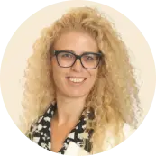 curly blonde woman with glasses smiling in a formal outfit, professional portrait with light background and circular frame