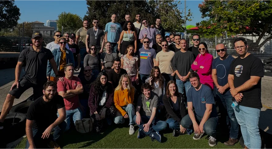 group photo of diverse people outdoors in casual attire, with greenery and urban backdrop, team gathering showcasing camaraderie and unity