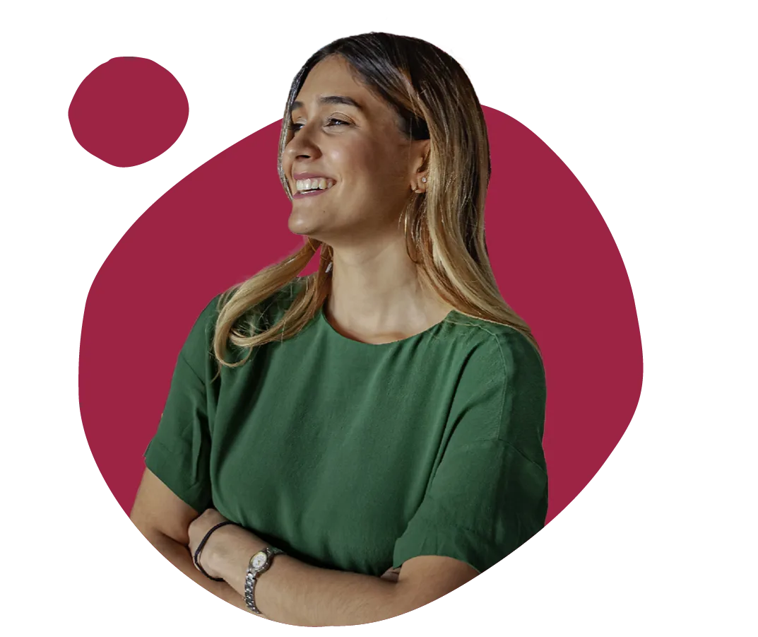 young woman smiling in a green top against a vibrant maroon background, casual portrait showcasing confidence and joy