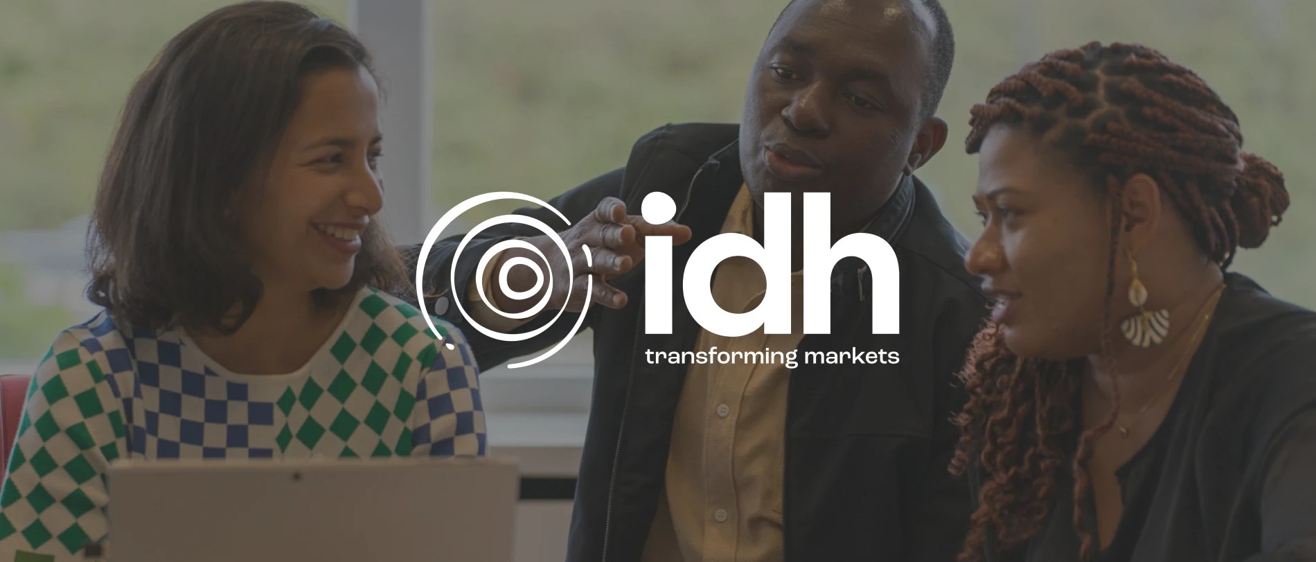 people engaging in discussion, idh logo with tagline, backgrounds of a work environment