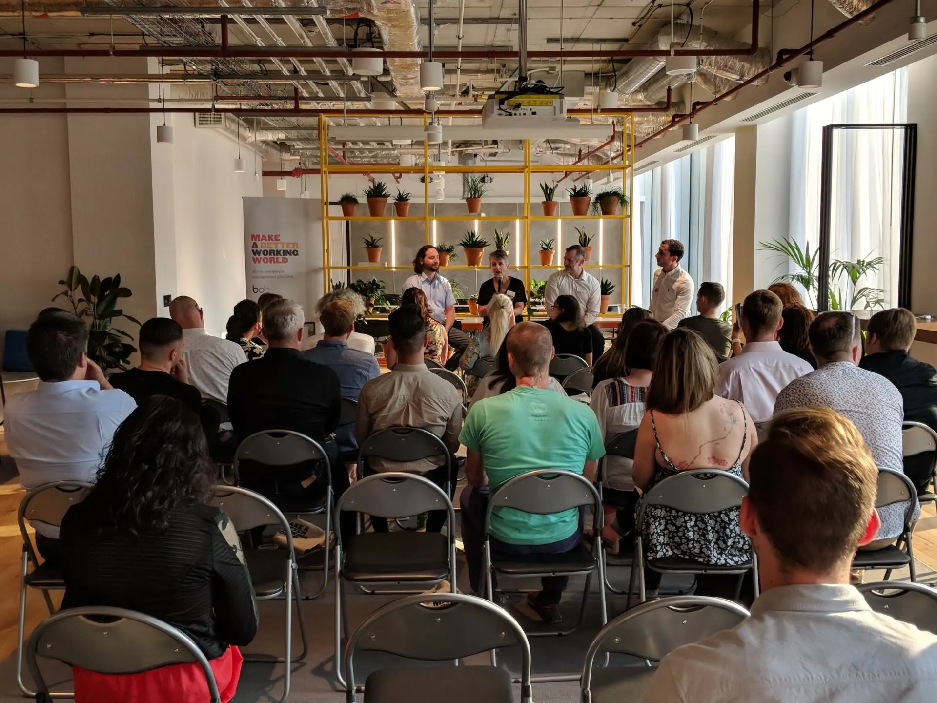 audience-listening-panel-discussion, modern-office-space-with-plants