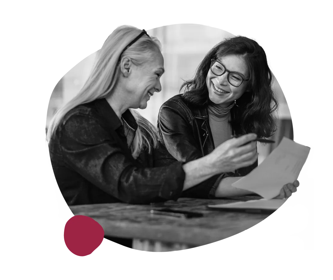 smiling women engaged in discussion over documents, professional collaboration in a modern workspace