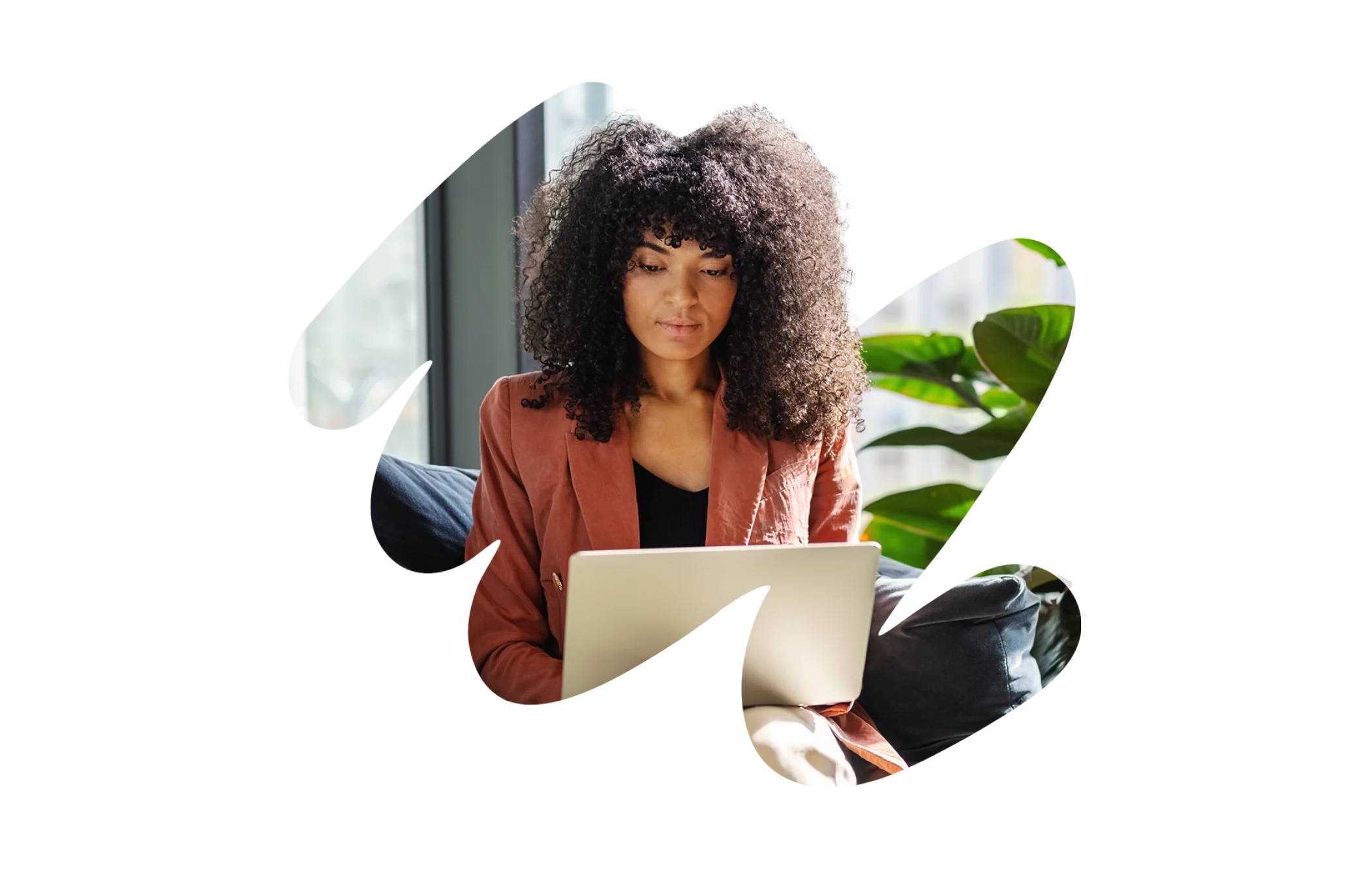 young woman with curly hair working on a laptop in a bright, modern space with plants, home office, remote work, technology