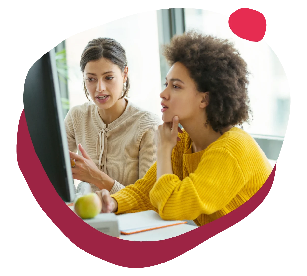 collaborative women discussing ideas at a computer workstation in a bright office, two women engaged in conversation and teamwork