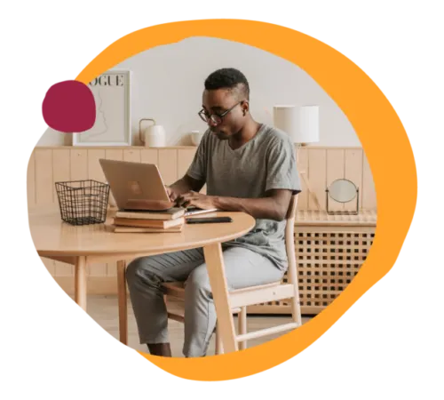 man working on a laptop at a modern wooden table in a cozy room, home office workspace with stylish decor and accessories