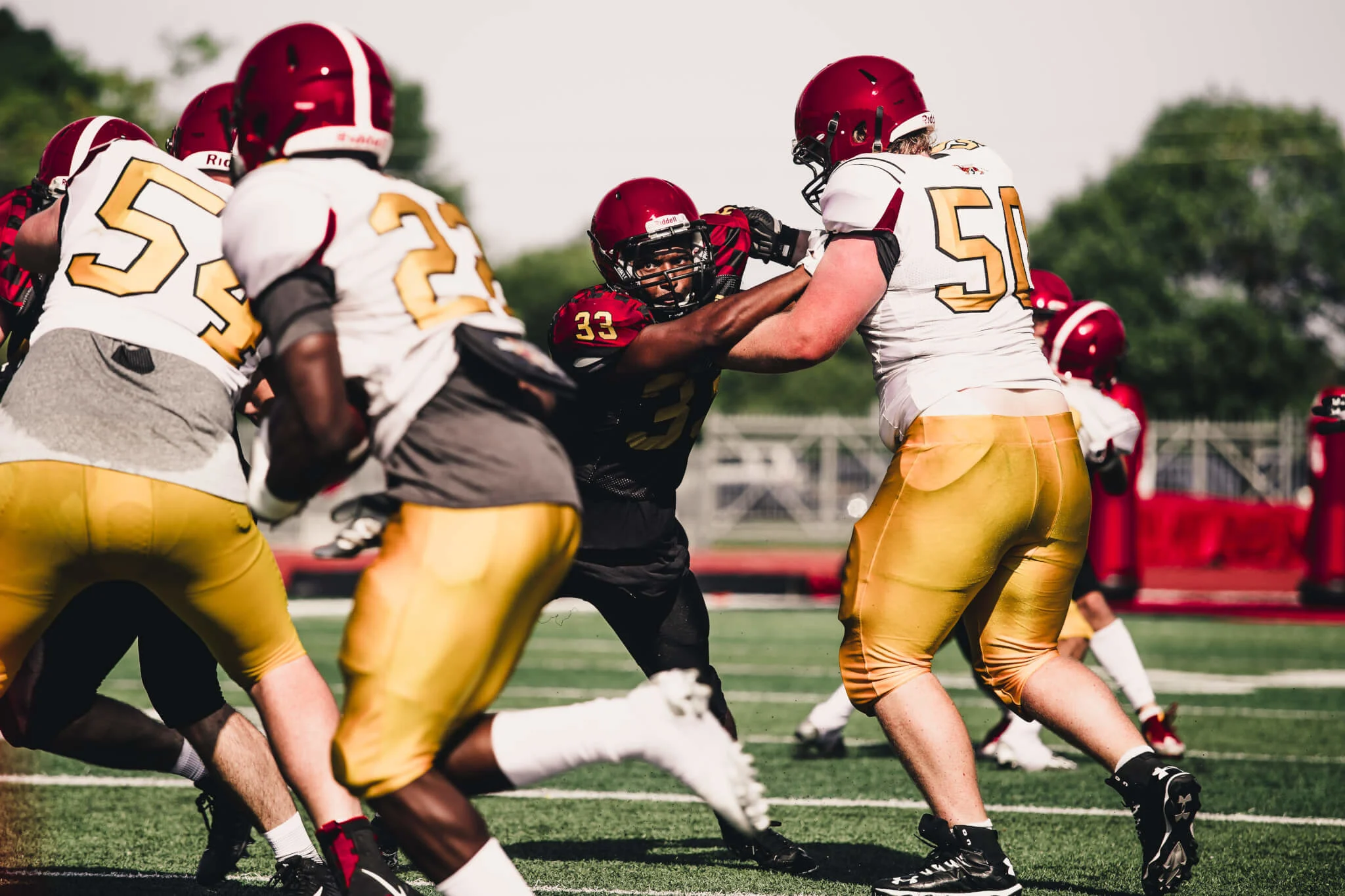 football players, intense scrimmage, team colors red and gold