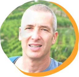 man smiling with shaved head in vineyard, green vineyard background with rows of grapevines and soft lighting